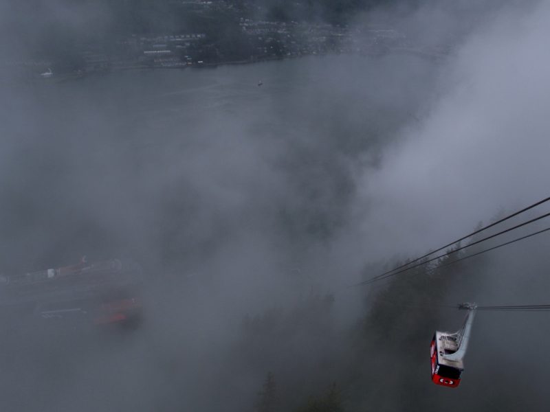 Red cable car descending through thick fog on a mountainside