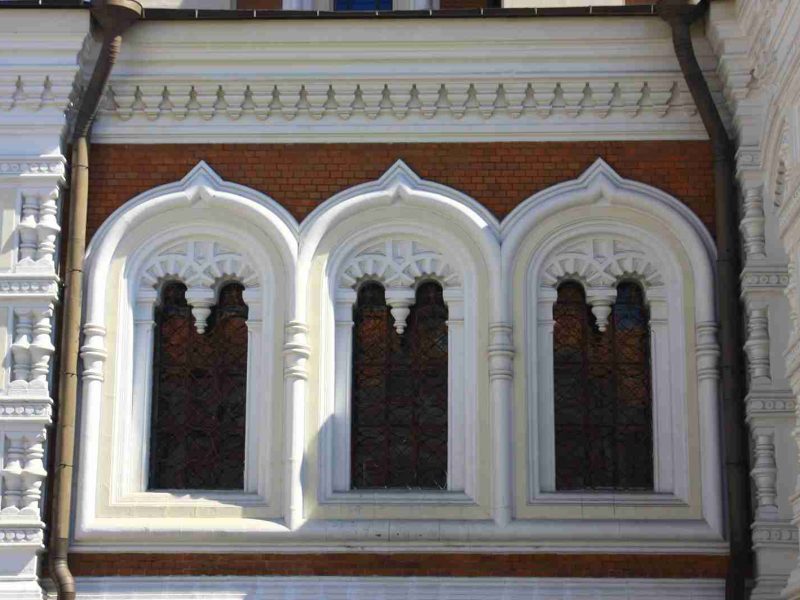 Close-up of ornate kokoshnik-style triple arched window with red brick and white stucco detailing