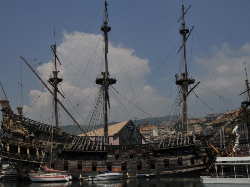 Ornate wooden galleon replica ship with tall rigged masts moored in a European harbor town